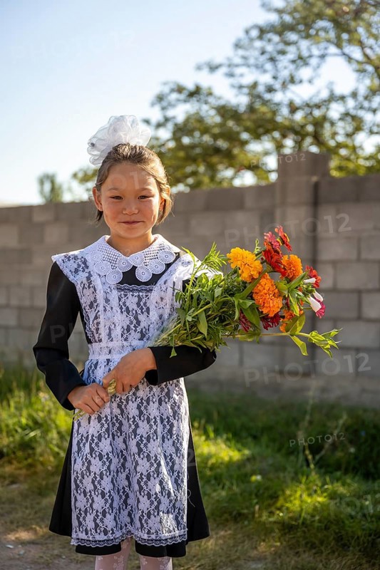 Schoolgirl with a bouquet of flowers on her first day at school, Issyk-Kul region, Kyrgyzstan, Asia