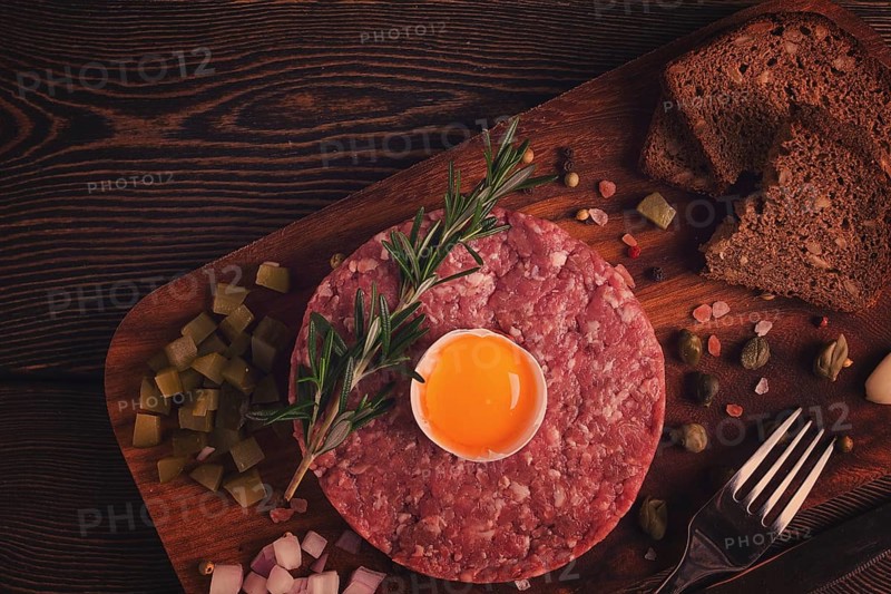 Beef tartare, with egg, capers, gherkins and bread, toned, top view, close up, horizontal, no people