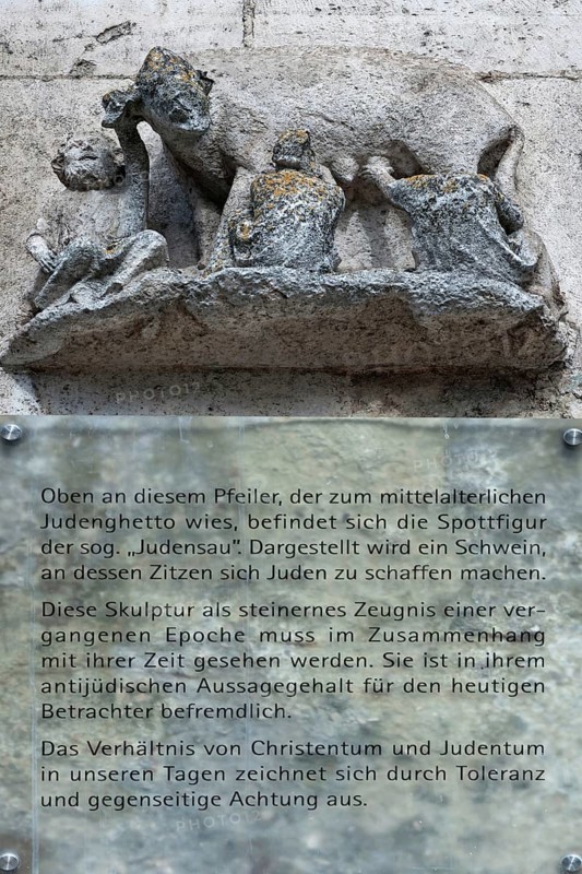 Medieval mocking figure of the so-called Judensau at St Peter's Cathedral, below information sign about the meaning, Regensburg, Upper Palatinate. Bavaria, Germany, Europe