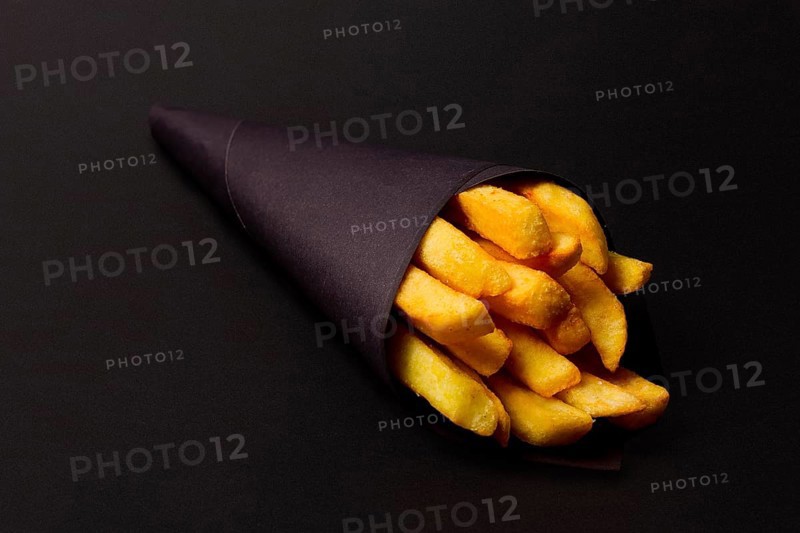 French fries, in black paper packaging, on a black background, close-up, selective focus