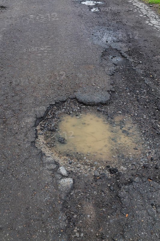 Pothole filled with rainwater on wet black asphalt road surface in spring, Montreal, Quebec, Canada, North America