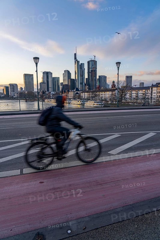Skyline of the city centre of Frankfurt am Main, cyclist on the Ignatz-Bubis-Bridge, dusk, river Main, winter, Hesse, Germany, Europe