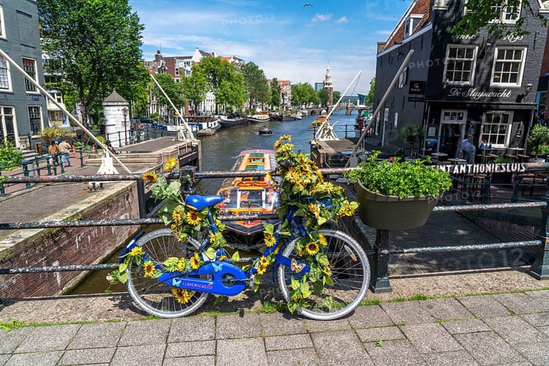 Sint Antoniesluis, on the Oudeschans canal, bicycle decorated with sunflowers, canal cruise boat, café, De Sluyswacht, Amsterdam, Netherlands