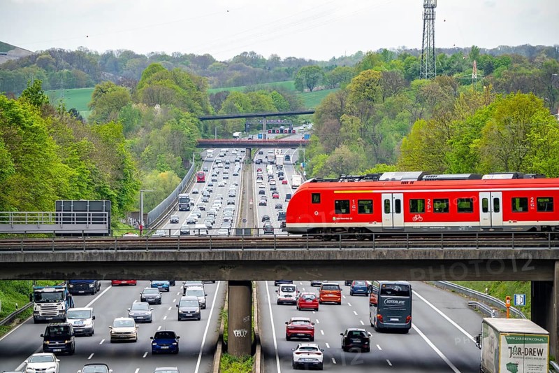 S-Bahn train crossing the motorway A3, traffic on 8 lanes, incl. the temporarily released hard shoulder, behind the motorway junction Hilden, view in north direction, near Erkrath, North Rhine-Westphalia, Germany, Europe