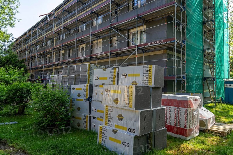 Energetic renovation of an apartment building, thermal insulation, building materials, insulation materials stored in front of the construction site, scaffolded building