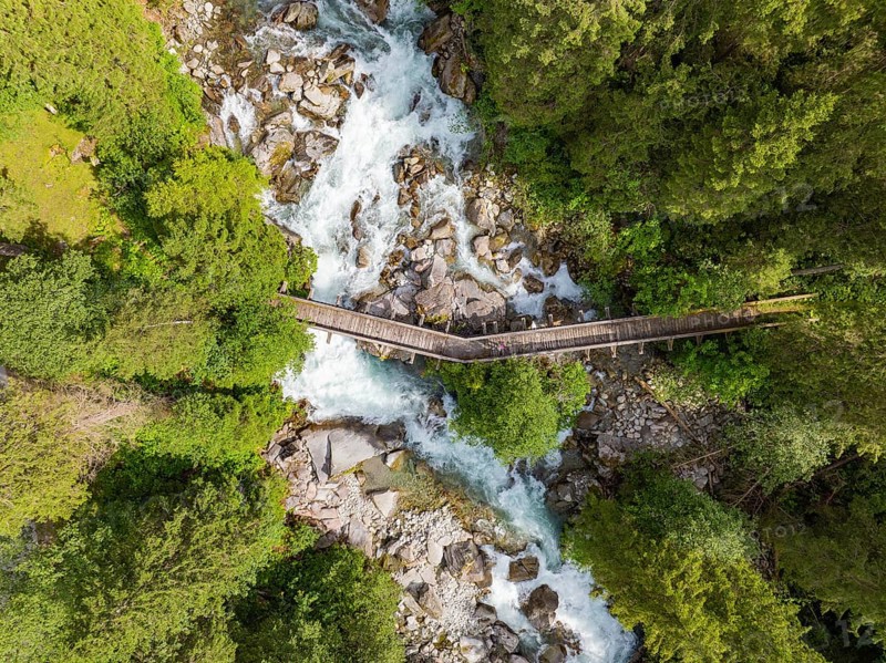 Aerial view of a wooden bridge over a raging river, surrounded by dense forest, Zillertal, Austria, Germany, Europe