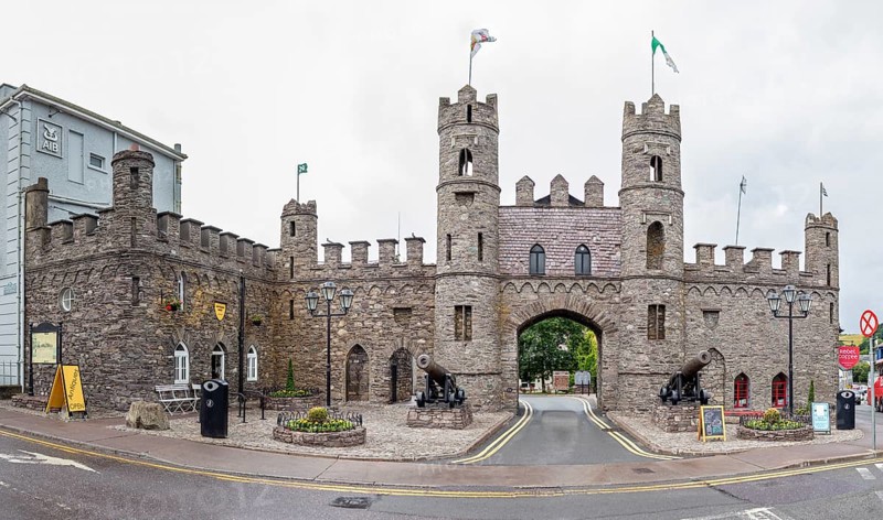 Imposing stone castle with flags and cannons, historical character on the street corner, Macroom