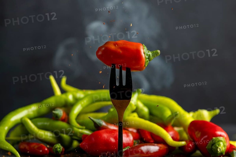 A red pepperoni on a fork, pepperoni and some smoke in the background, food photography