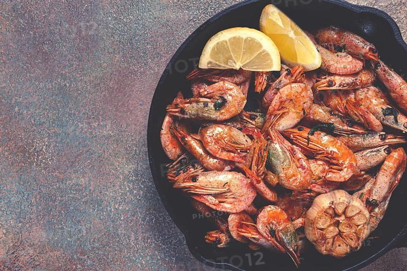 Fried shrimps, in a cast-iron pan, shrimps for beer, in a newspaper, on a gray table, there are no people