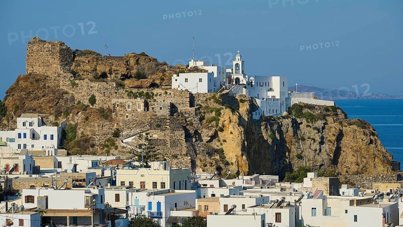 Panoramic view of a Mediterranean town with white buildings and a church on a rock, with the blue sea in the background in sunny weather, morning light, Panagia Spiliani, Castle, Mandraki, Nisyros, Dodecanese, Greek Islands, Greece, Europe