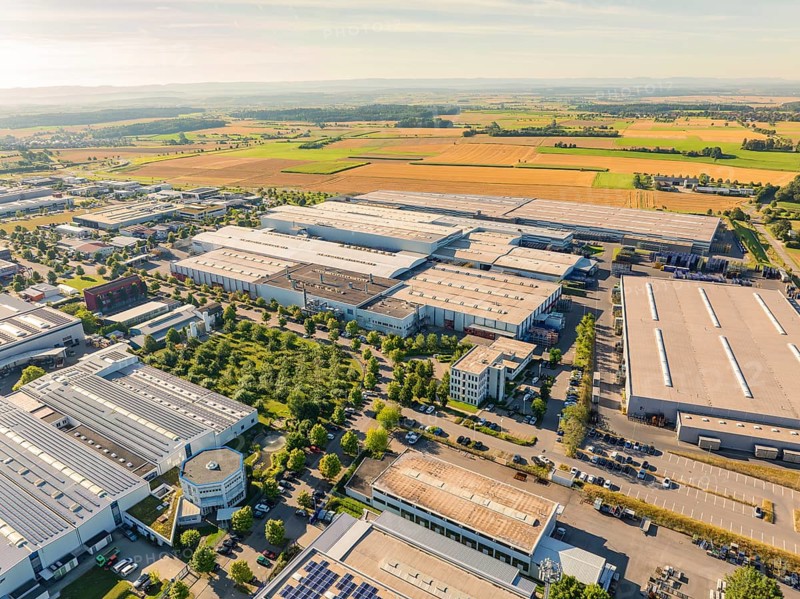 Industrial area with several large buildings, surrounded by green fields and trees, a bright and spacious sky above, Industrial area Wolfsberg, Nagold, Black Forest, Germany, Europe