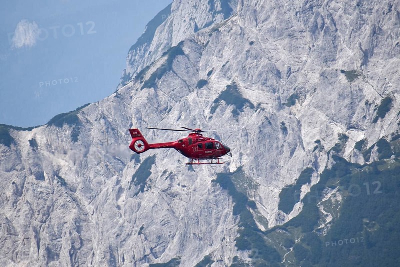 Airbus H135 helicopter in use as a rescue helicopter for the emergency doctor and the mountain rescue service, flying in front of the rock faces of the horse-rider Alm above the Klausbachtal in the Berchtesgaden National Park, Bavaria, Germany, Europe