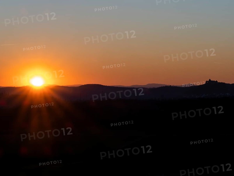 Sunset over the Kellerwald national park in autumn, with the town of Waldeck church and surrounding buildings, as a silhouette on the horizon, North Hesse, Germany, Europe