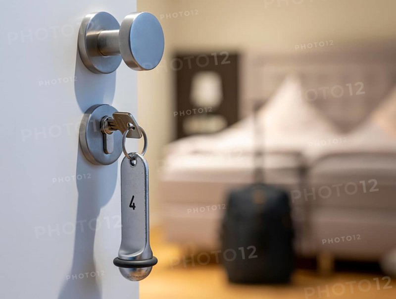 Symbolic image of a hotel, key inserted in the door of a hotel room, analogue lock
