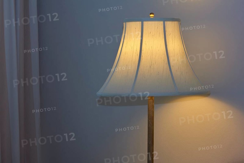 A warmly illuminated bedside lamp with a white shade, cosy