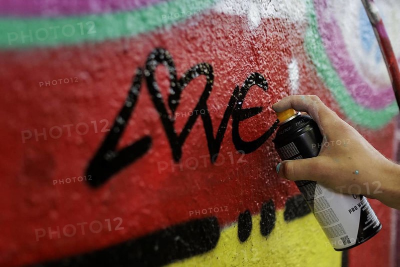 A man sprays graffiti on a wall with a spray can. Berlin, 14.08.2024