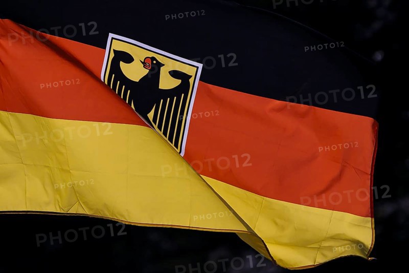 Symbolic photo. The national flag of the Federal Republic of Germany with a federal eagle fluttering in the wind against the light. Berlin, 21 August 2024