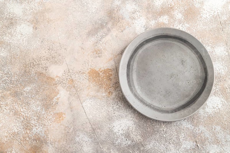 Empty gray ceramic plate on gray concrete background. Top view, copy space, flat lay