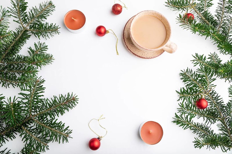 Christmas or New Year frame composition. Decorations, red balls, fir and spruce branches, cup of coffee, candles on a white paper background. Top view, copy space, flat lay