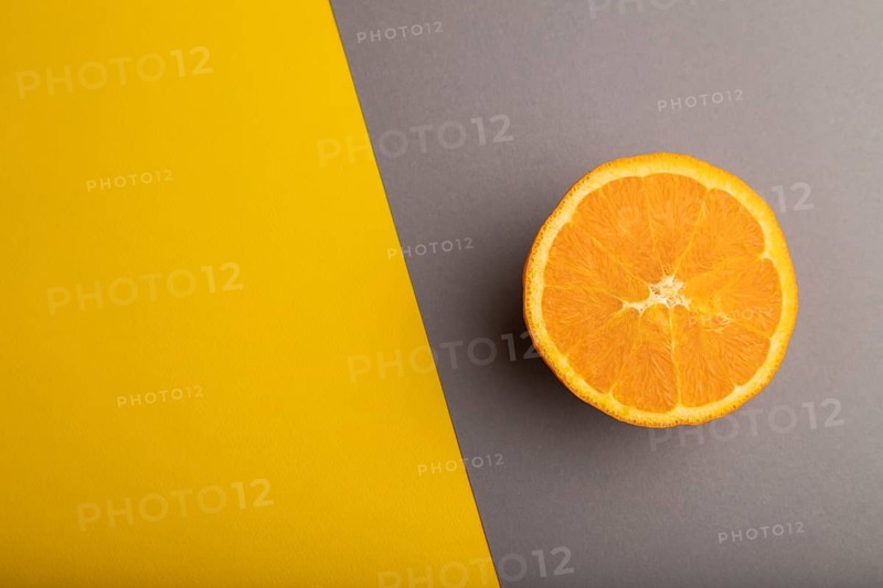 Ripe cut orange on gray and yellow pastel background. Top view, flat lay, copy space. Tropical, healthy food, concept, minimalism