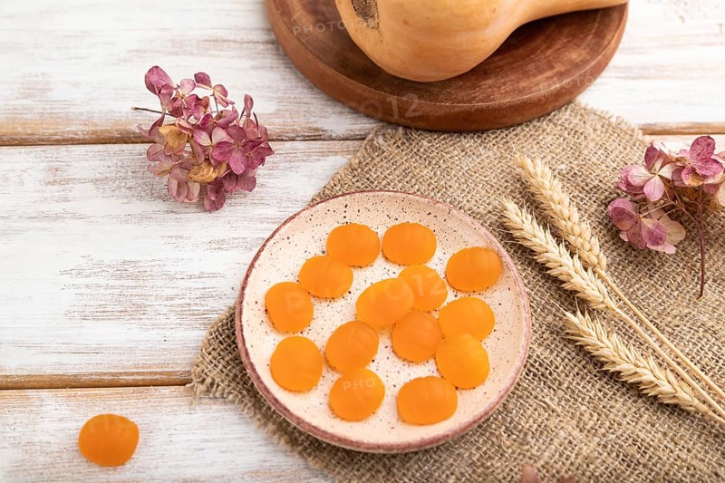 Jelly pumpkin candies on white wooden background and linen textile. selective focus, close up, side view. autumn concept