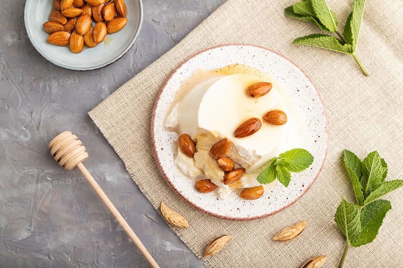 Ricotta cheese with honey and almonds on gray concrete background and linen textile. top view, flat lay, close up
