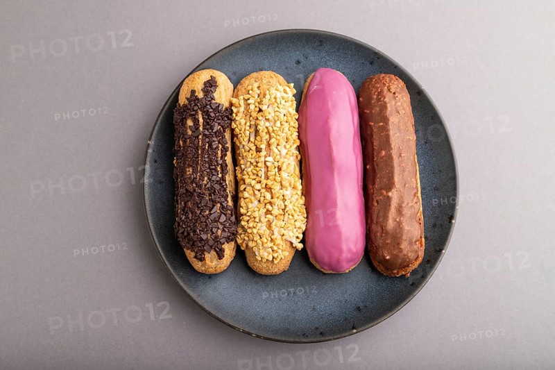 Set of eclair, traditional french dessert on blue ceramic plate on gray pastel background. top view, flat lay, close up, still life. Breakfast, morning, concept