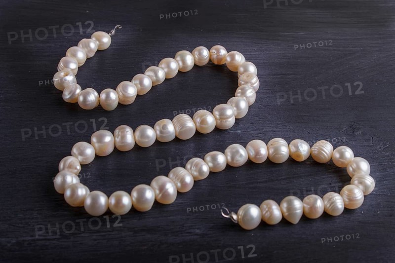 Caramel colored pearl beads on a black background. top view, close up