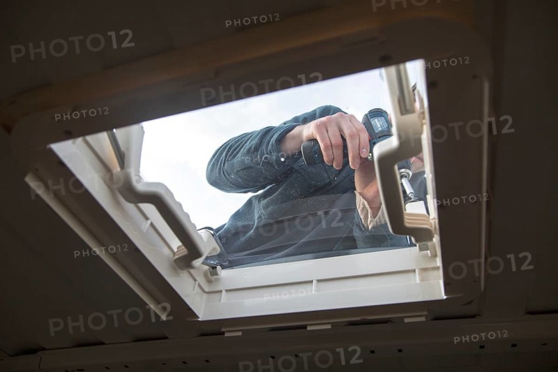 Cutting through roof of white metal camper van conversion to install ventilation window, UK