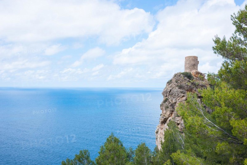 Torre des Verger, also Torre del Verger, Torre de ses Ànimes, old watchtower, lookout tower on a rock with peaceful sea view, trees in spring, spring, pine trees (Pinus), calm, wide, blue sea under a blue sky with white clouds, distant horizon, Mediterranean Sea on the northwest coast, Banyalbufar, Serra de Tramuntana, Majorca, Spain, Europe
