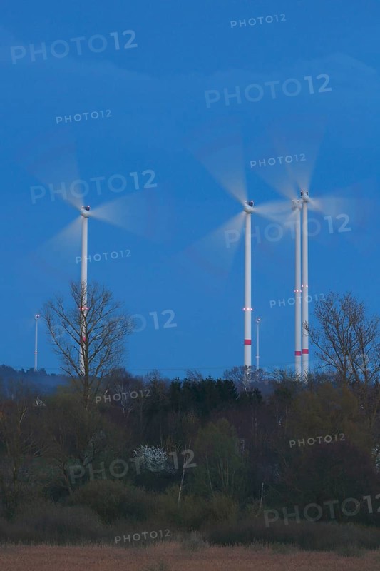 Wind energy systems turn in the evening light over a landscape framed by trees, wind turbines in the evening light, long exposure, Flusslandschaft Peenetal nature park Park, Mecklenburg-Western Pomerania, Germany, Europe