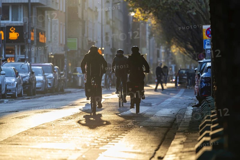 Cyclists in oblique sunlight in November, poor visibility, danger of glare, cycle lane, cyclists have priority over motor traffic, Cologne, North Rhine-Westphalia, Germany, Europe