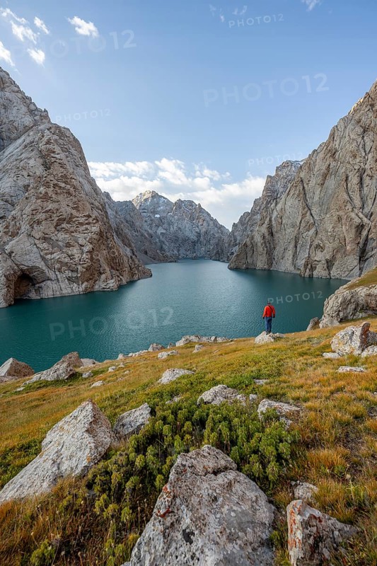 Tourist at the blue mountain lake between rocky steep mountain peaks, Kol Suu Lake, Sary Beles Mountains, Naryn Province, Kyrgyzstan, Asia