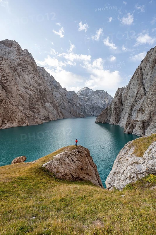 Tourist at the blue mountain lake between rocky steep mountain peaks, Kol Suu Lake, Sary Beles Mountains, Naryn Province, Kyrgyzstan, Asia