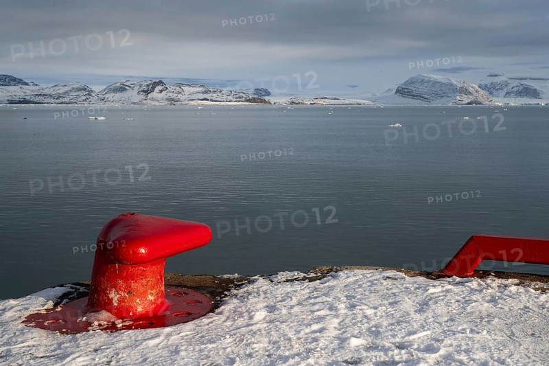 Red bollard in front of the wintry, snow-covered Kongsfjorden, harbour, Ny-Ålesund, Spitsbergen Island, Svalbard and Jan Mayen archipelago, Norway, Europe