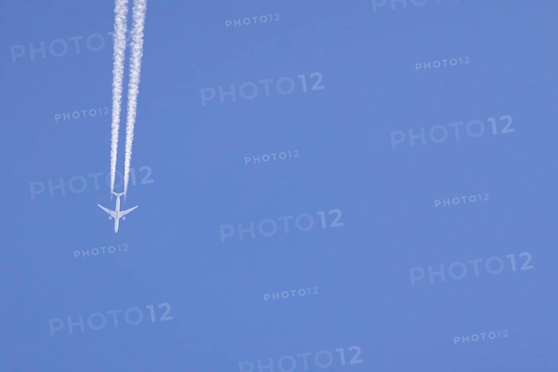 Airbus aircraft of Qatar airways flying across a blue sky with a vapour trail or contrail behind, England, United Kingdom, Europe