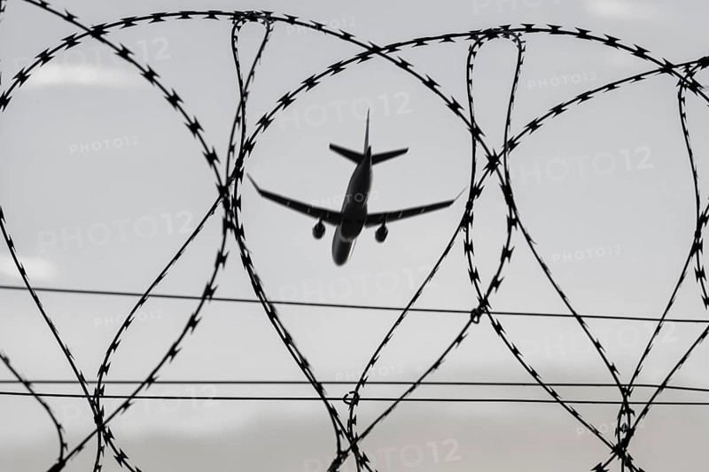 Symbolic image, deportation flights of illegal and delinquent migrants, refugees, passenger aircraft, airport, security fence, barbed wire, black and white image, Germany, Europe