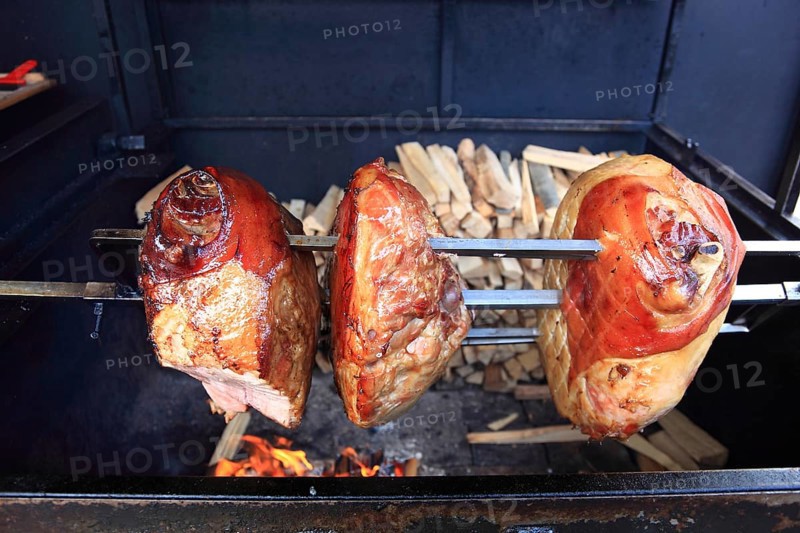 Pork knuckles are grilled on a spit over a wood fire