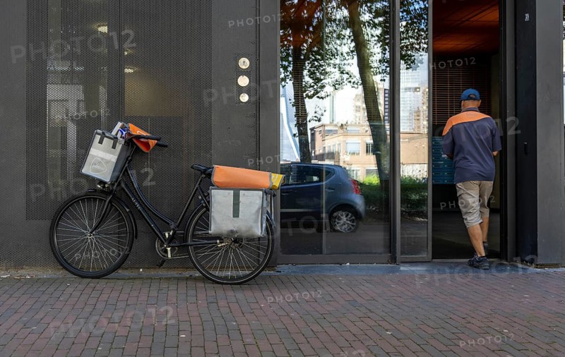 Dutch Post deliverer, with bicycle, in Rotterdam, Netherlands