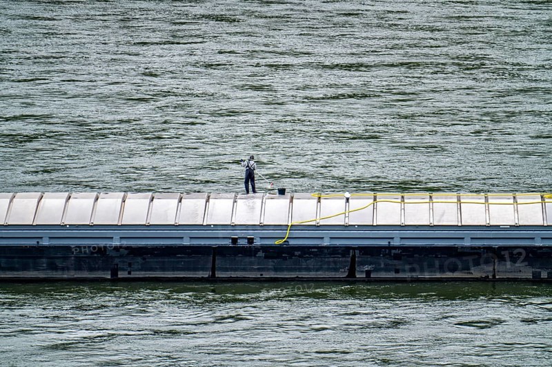 Inland waterway vessel, freighter, with closed cargo hatches, employee cleans the deck with water and scrubbing brush, on the Rhine, Rhineland-Palatinate, Germany, Europe