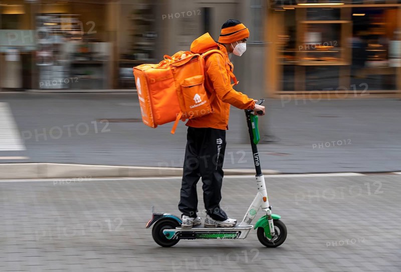 Delivery service Lieferando.de, delivery courier with e-scooter in the city centre, Rathenaustraße, in Bochum, North Rhine-Westphalia Germany