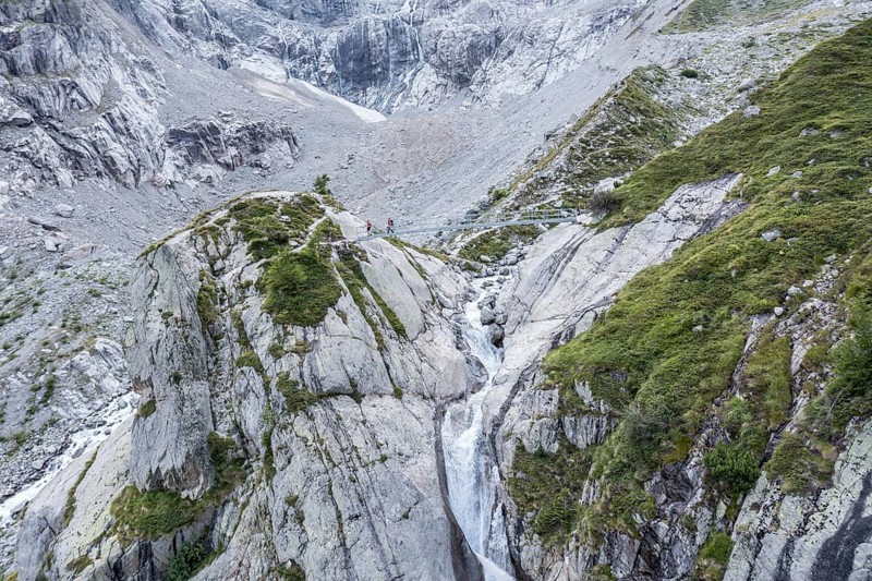 Aerial view, hikers on bridge over glacial stream, large single rock, hiking path from La Fouly to Cabane de Neuve, Valley Val Ferret, Valais, Wallis, Switzerland, Europe
