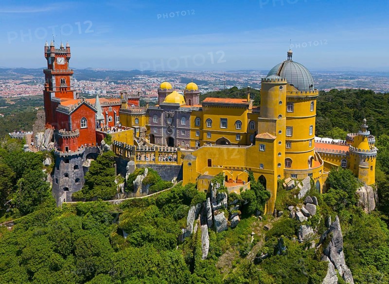 Magnificent castle with colourful towers and buildings in a green, hilly landscape under a blue sky, aerial view, Palácio Nacional da Pena, National Palace Pena, Sintra, Lisbon, World Heritage Site, UNESCO, Portugal, Europe