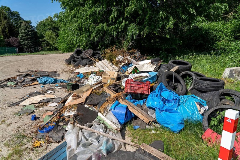 Illegally disposed waste, car tyres, building rubble, household waste, clothing, on a path next to a main road in Bochum, North Rhine-Westphalia, Germany, Europe
