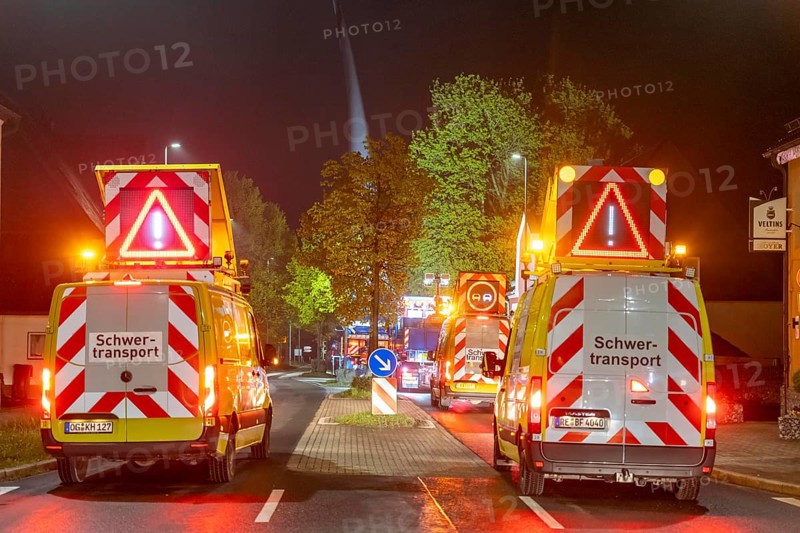 Securing and escort vehicles during the transport of a 68 metre long, 22 tonne blade of a wind turbine, here in Breckerfeld-Waldbauer, with a self-propelled blade-lifter vehicle, over a 40 km route, over 2 nights, in the Bergisches Land, through towns, villages, on country roads, narrow through roads, to the construction site of the wind turbine near Hagen, North Rhine-Westphalia, Germany, Europe