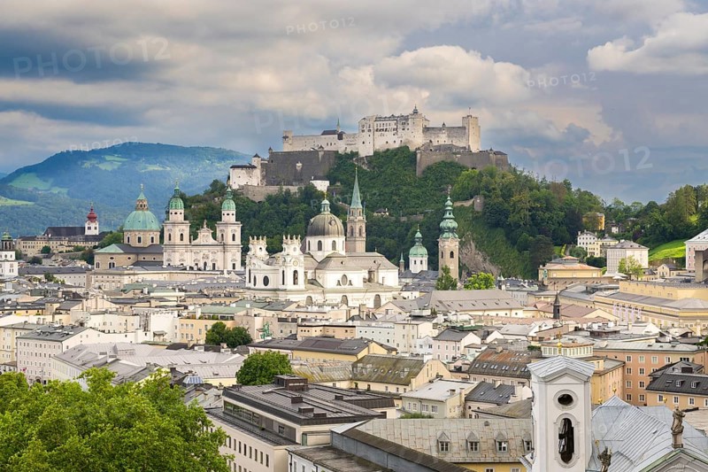 View of Salzburg with Hohensalzburg Fortress in the background and the historic city centre in the foreground, surrounded by mountains under a cloudy sky, Salzburg, Salzburger Land, Austria, Europe