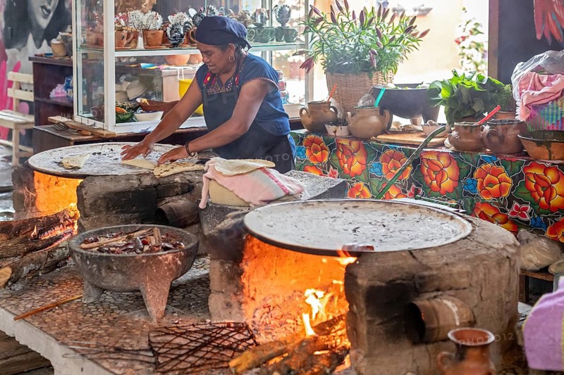 Santa María del Tule, Oaxaca, Mexico, A worker at the Restaurant Familiar Reynita cooks on a comal over a wood fire, Central America