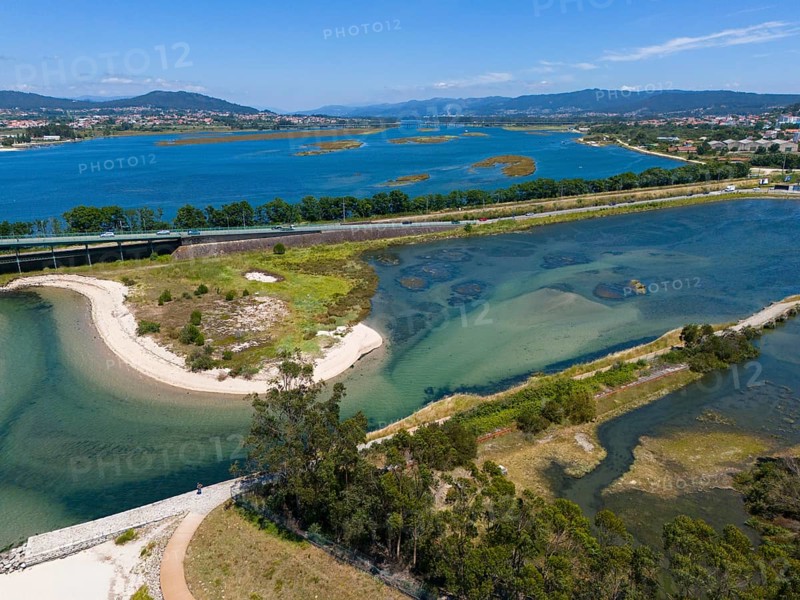 A natural area criss-crossed by rivers and islands with blue water and mountains in the background, aerial view, Lima River, Viana do Castelo, Portugal, Europe