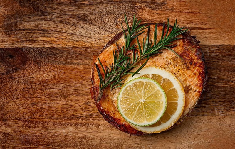 Salmon steak, fried, on a cutting board, top view, rosemary, lemon and lime, homemade, one serving, no people