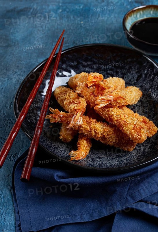 Shrimp in tempura, deep fried, on a black plate, with soy sauce, close-up, top view, no people